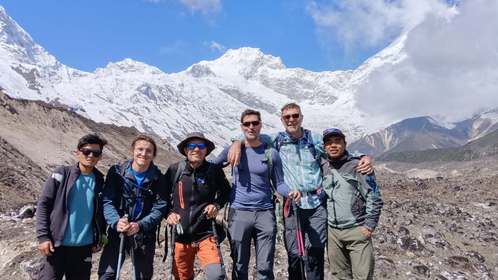 Trekkers walking through the remote Manaslu region with dramatic views of Mount Manaslu, surrounded by rugged trails, alpine terrain, and snow-capped peaks under a clear sky.