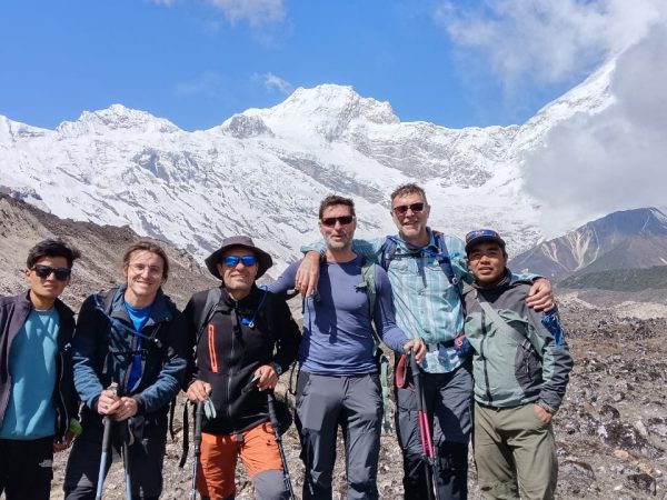 Trekkers walking through the remote Manaslu region with dramatic views of Mount Manaslu, surrounded by rugged trails, alpine terrain, and snow-capped peaks under a clear sky.